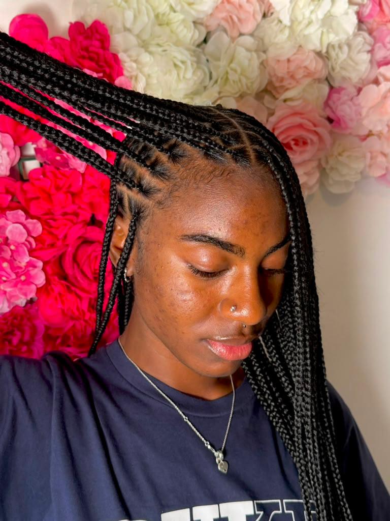 Long black braids styled against a flower wall